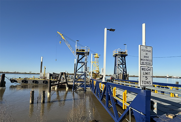 The structure in the image is a vehicle ferry terminal landing, specifically identified in search results as the Pointe a la Hache ferry landing in Louisiana. The signs indicate safety regulations for vehicles using the ferry and the bridge.