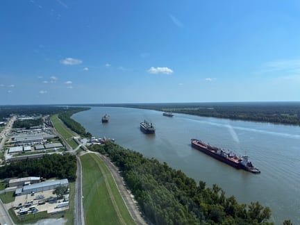 Aerial perspective of the Louisiana Gateway Port showing the proximity of river shipping lanes to parallel rail lines and industrial warehouses, highlighting intermodal logistics.